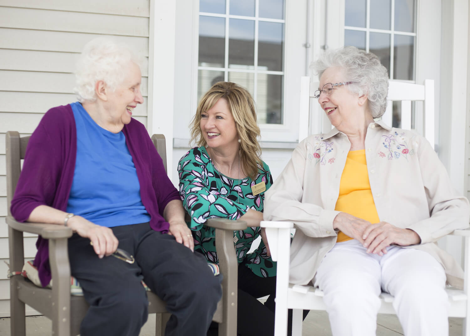 Two residents and a caregiver sitting outside together