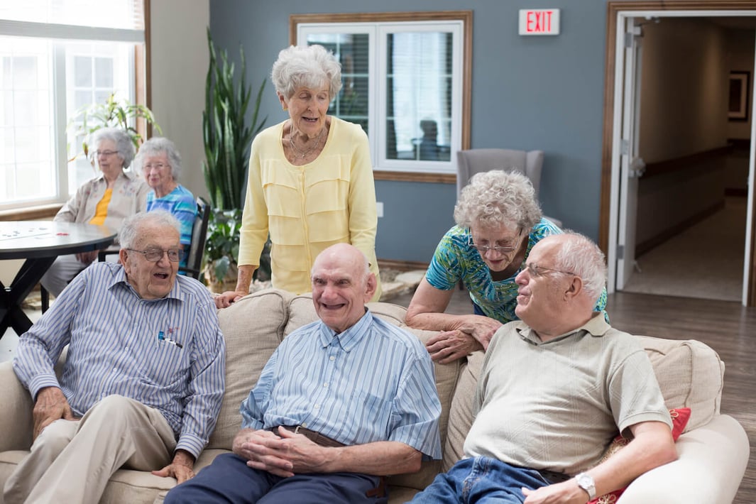 Group of five seniors socializing in the community living room 