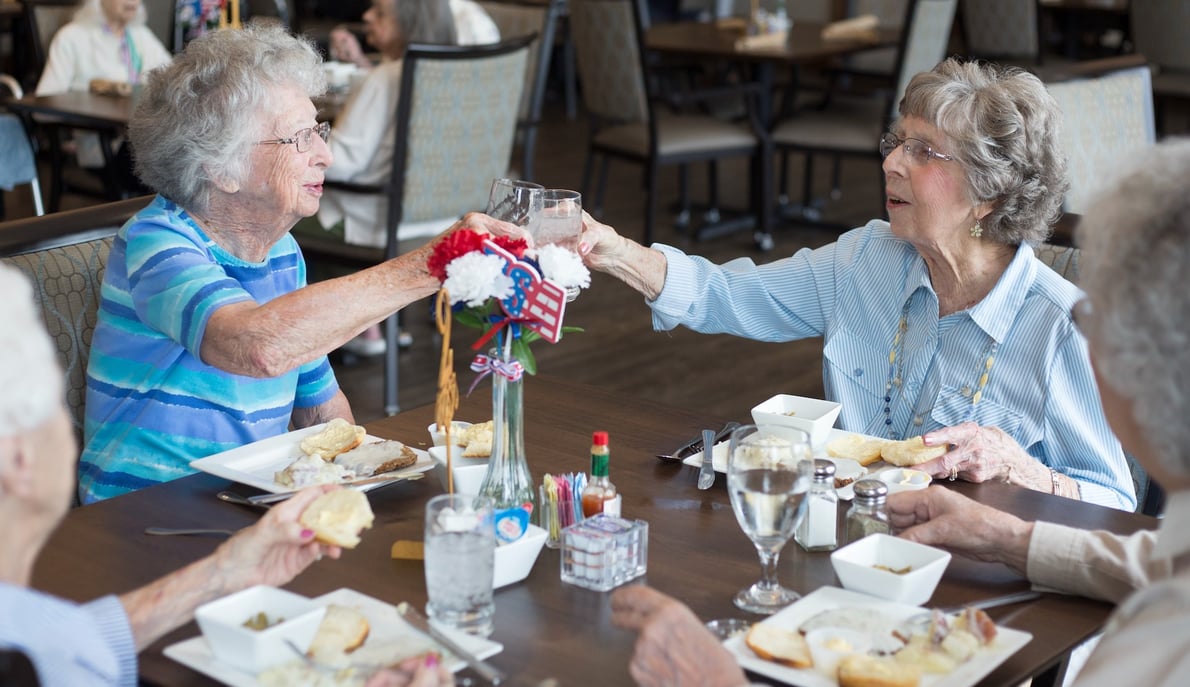 Senior women sharing a toast during a meal in the community restaurant