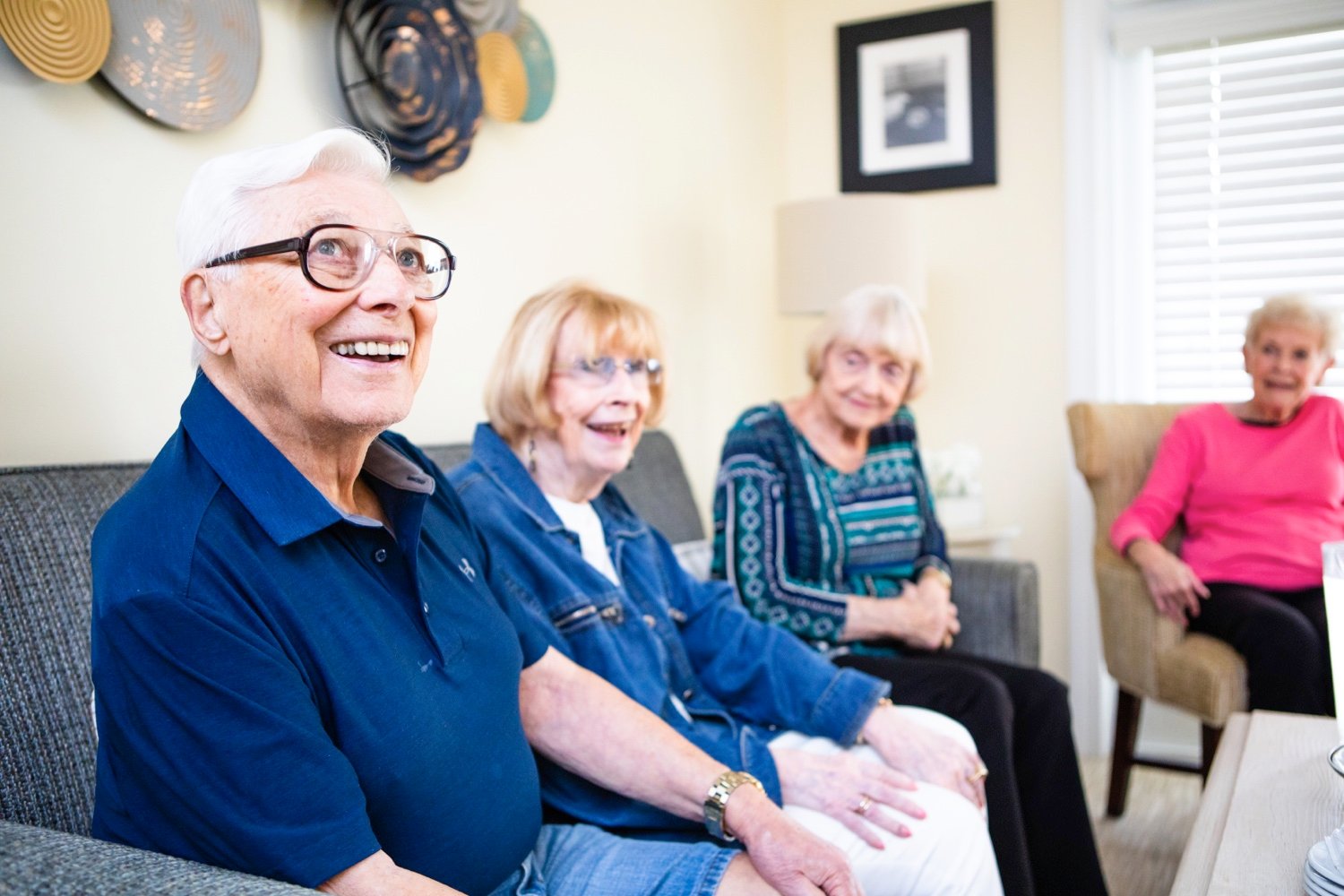 A group of seniors laughing and socalizing in a living room
