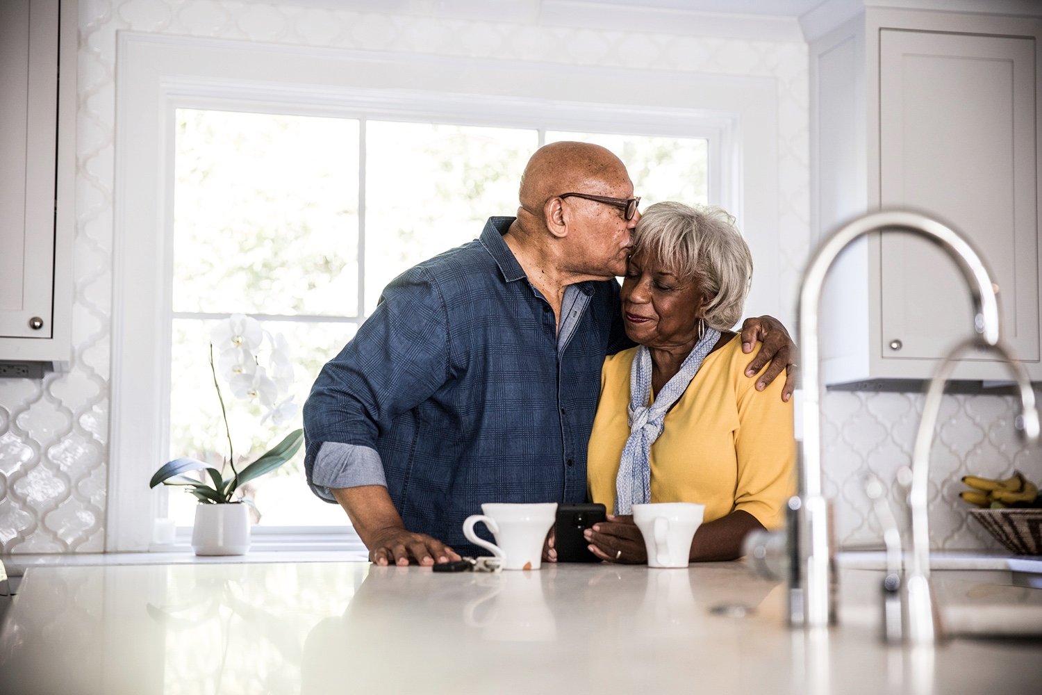 A happy senior couple embracing in a kitchen