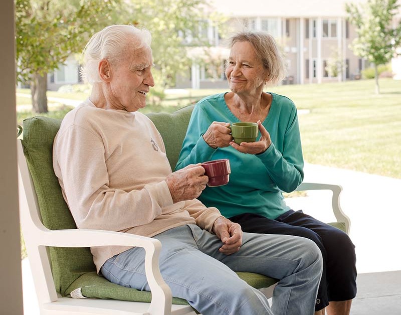 Seniors drinking coffee outside on a bench