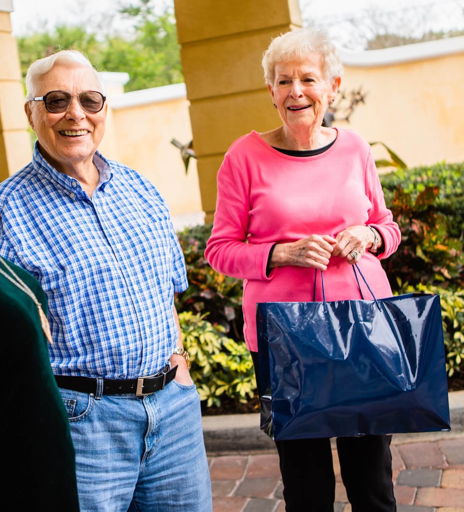 A senior couple returning with shopping bags to the community entrance