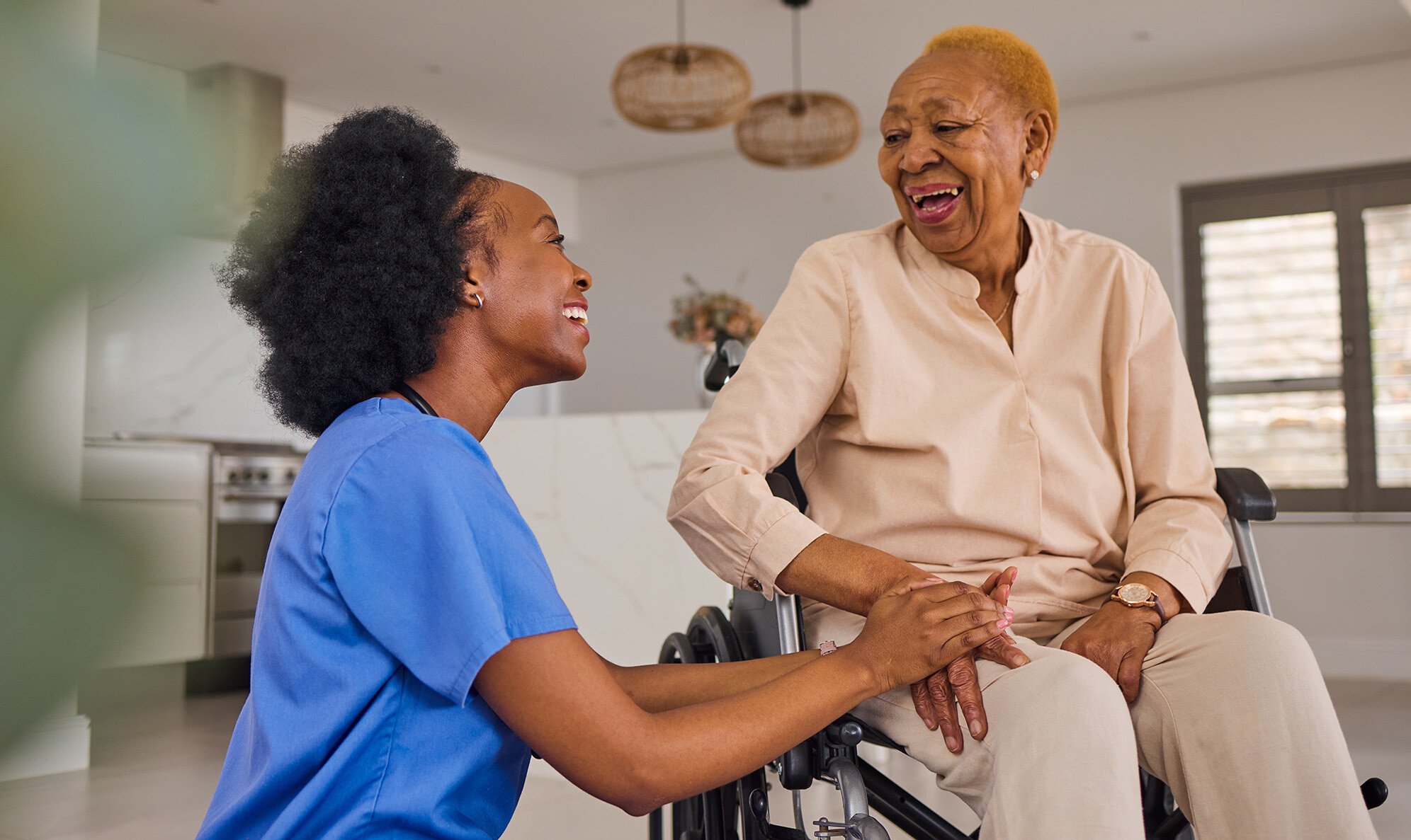Senior woman in a wheelchair holding hands and smiling with caregiver