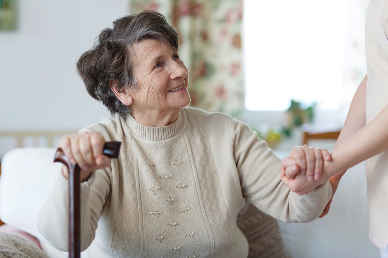 Senior woman holding hands with and looking at her caregiver