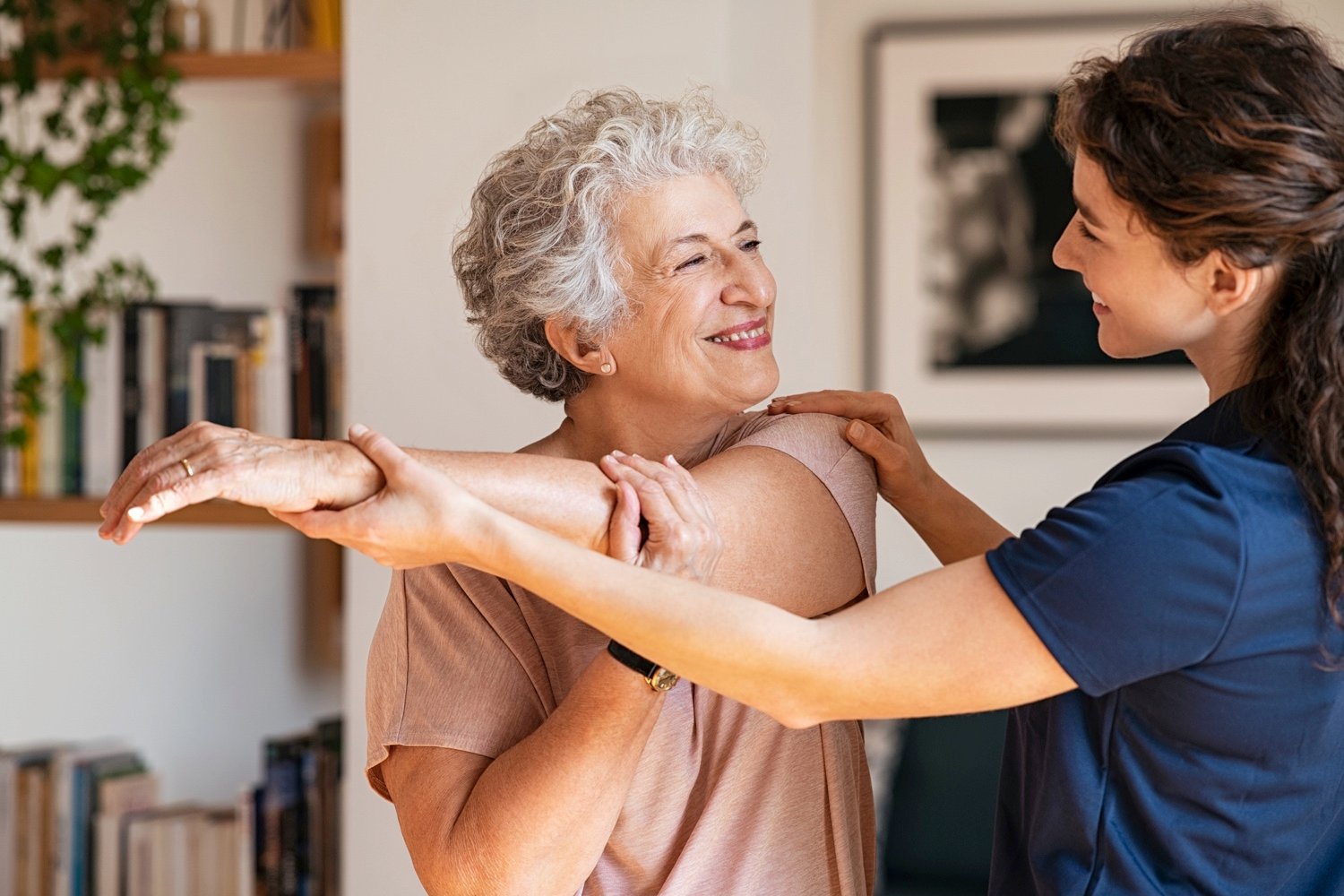 Senior woman with trainer exercising at home-1296176738
