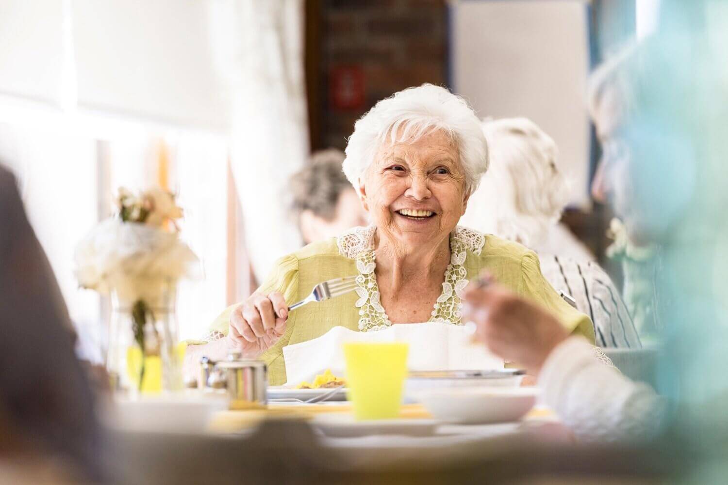 Senior woman eating lunch with friends in the community restaurant