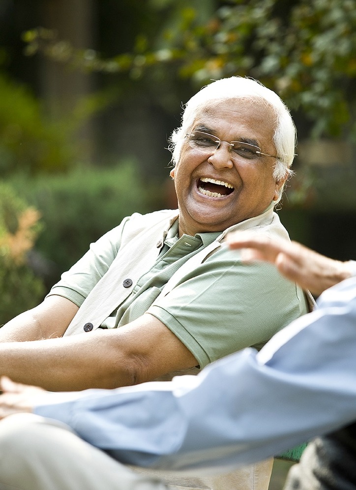 Two senior men laughing on a park bench