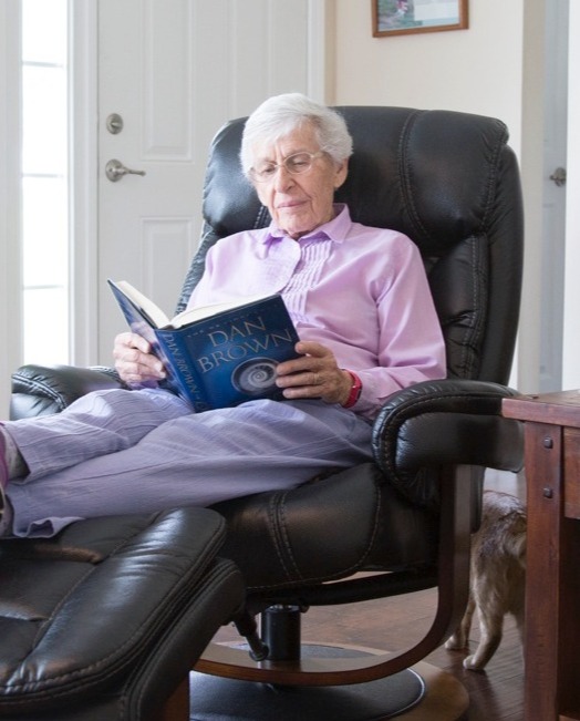 Resident reading in a leather chair in her living room