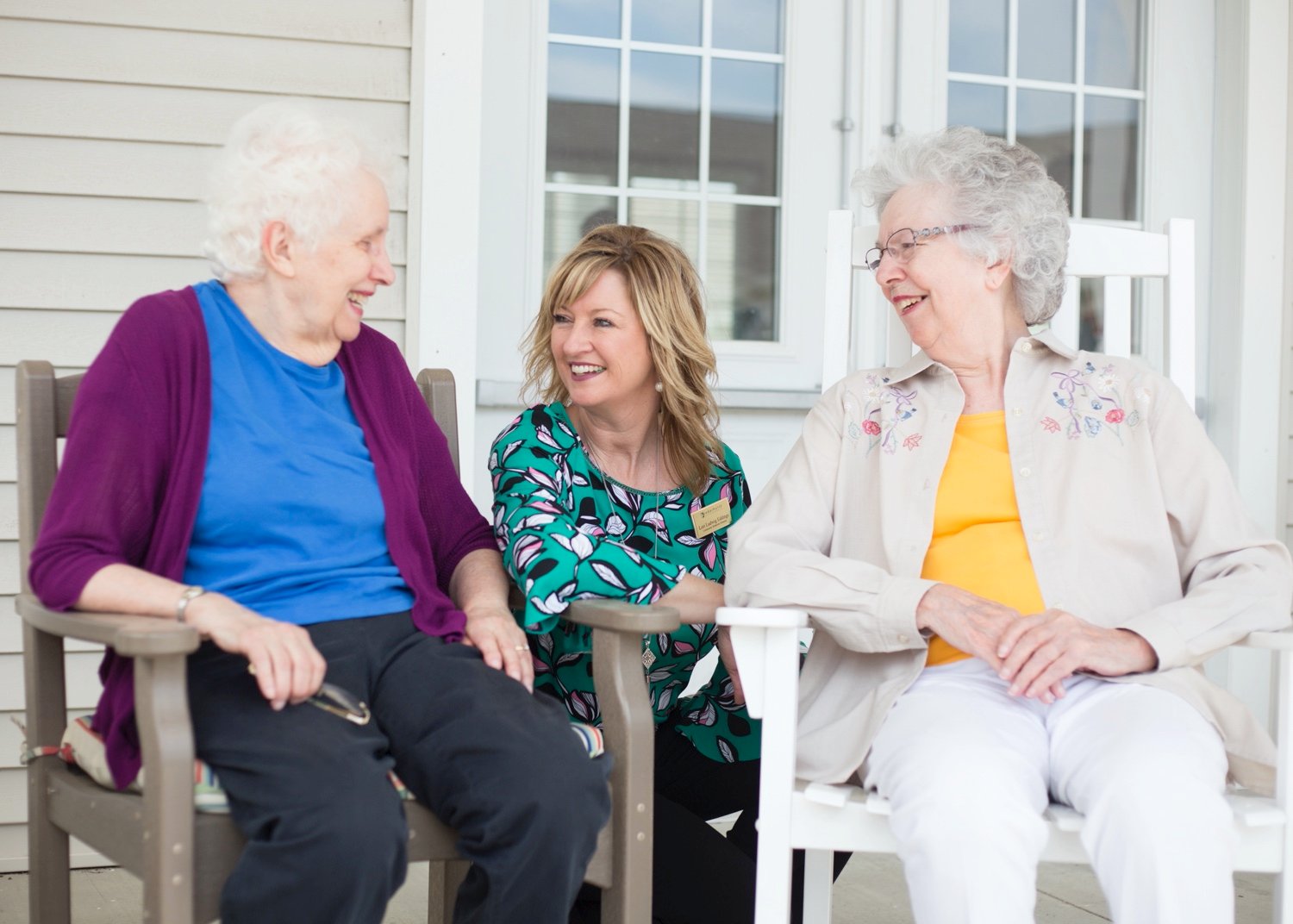 A staff member socializing on the patio with two senior women