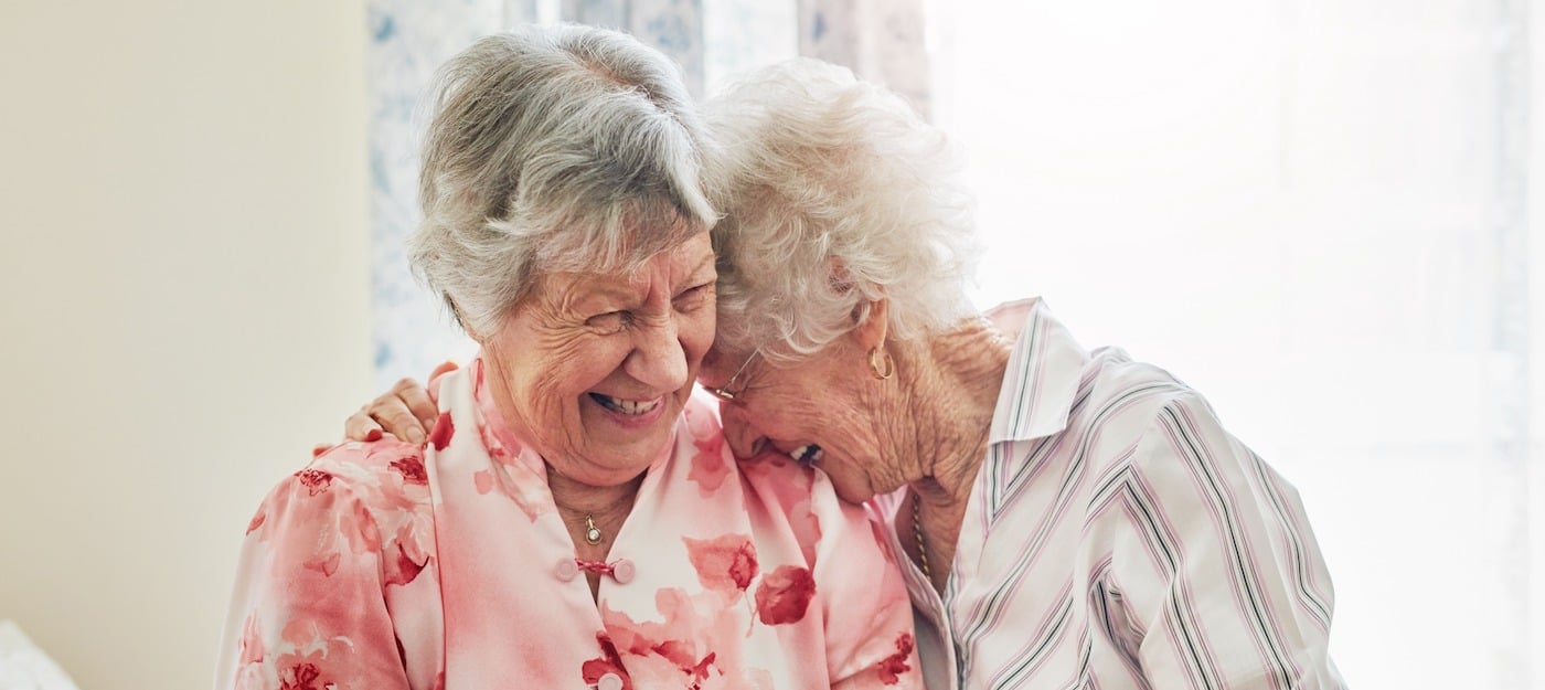 Two senior women laughing together and embracing