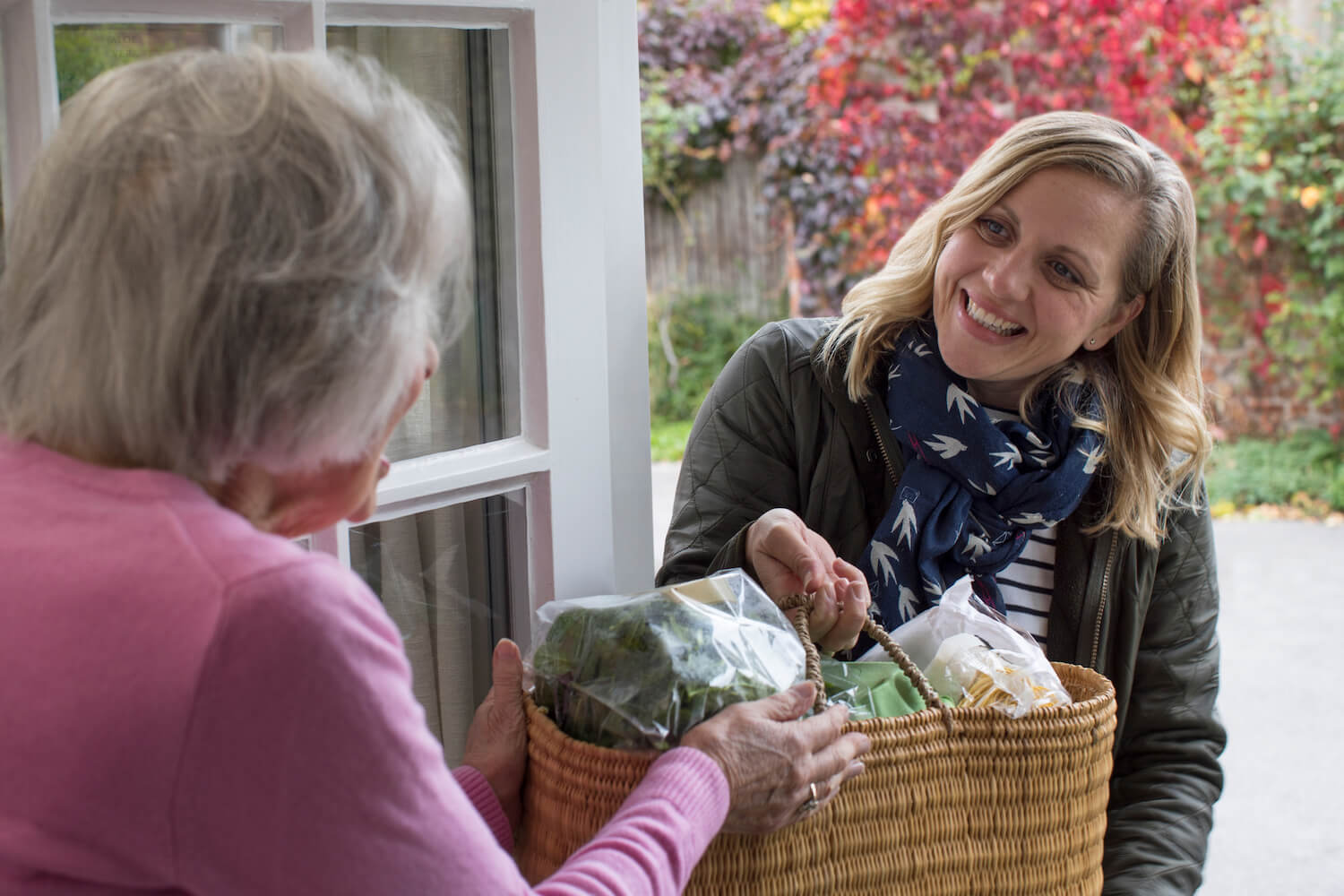 Woman bringing groceries to a senior's front door