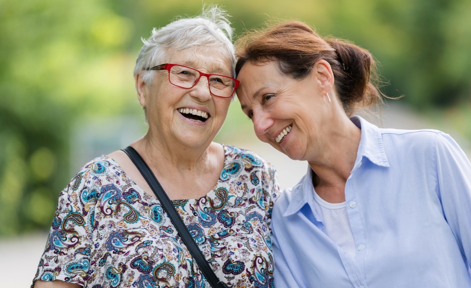 Senior woman laughing outside with a staff member