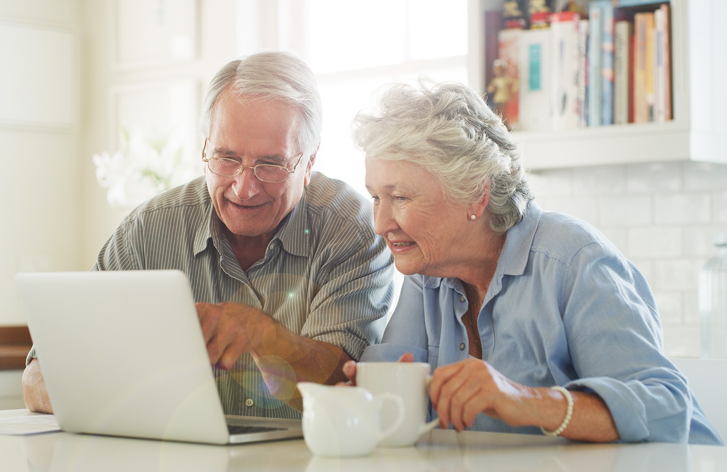 Senior couple looking at a laptop computer together while drinking coffee
