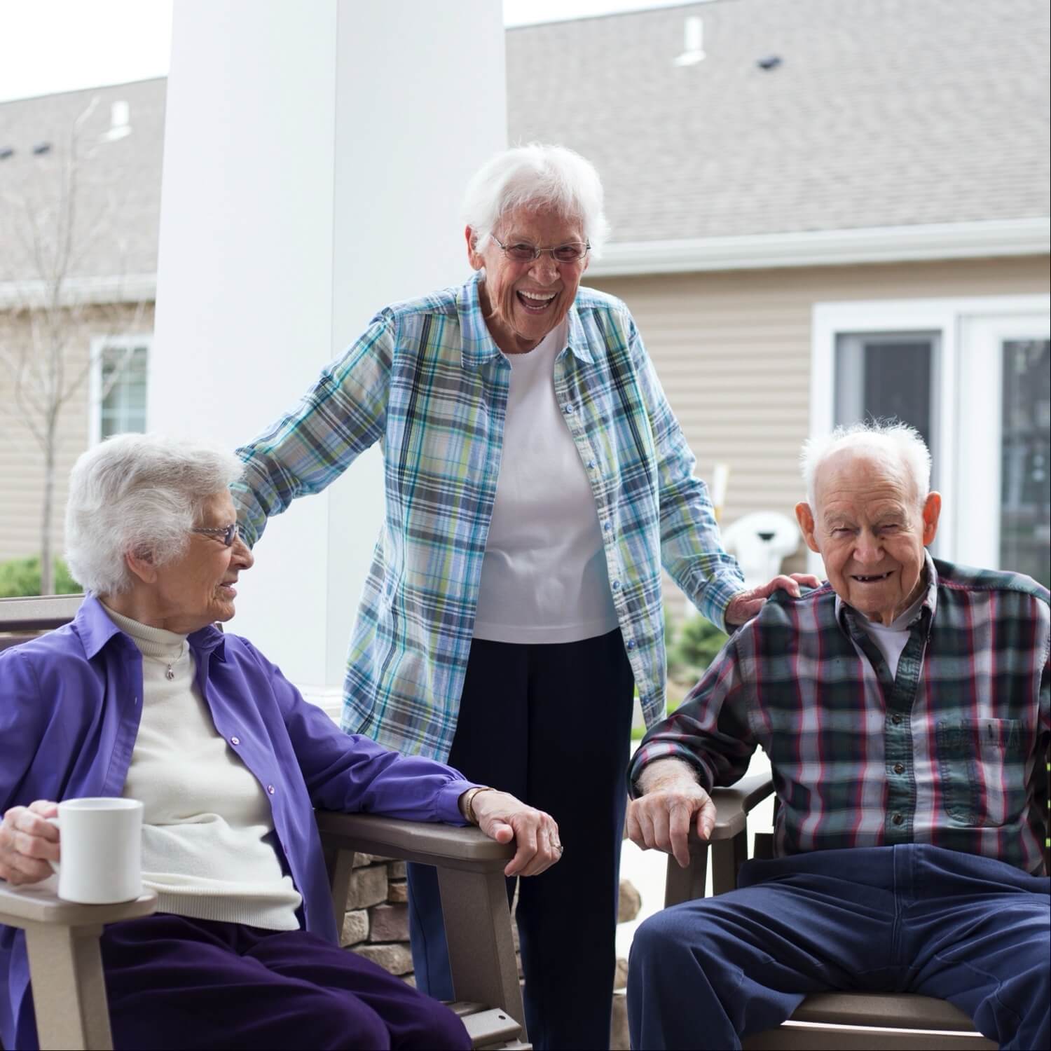 Three senior residents laughing on the community porch