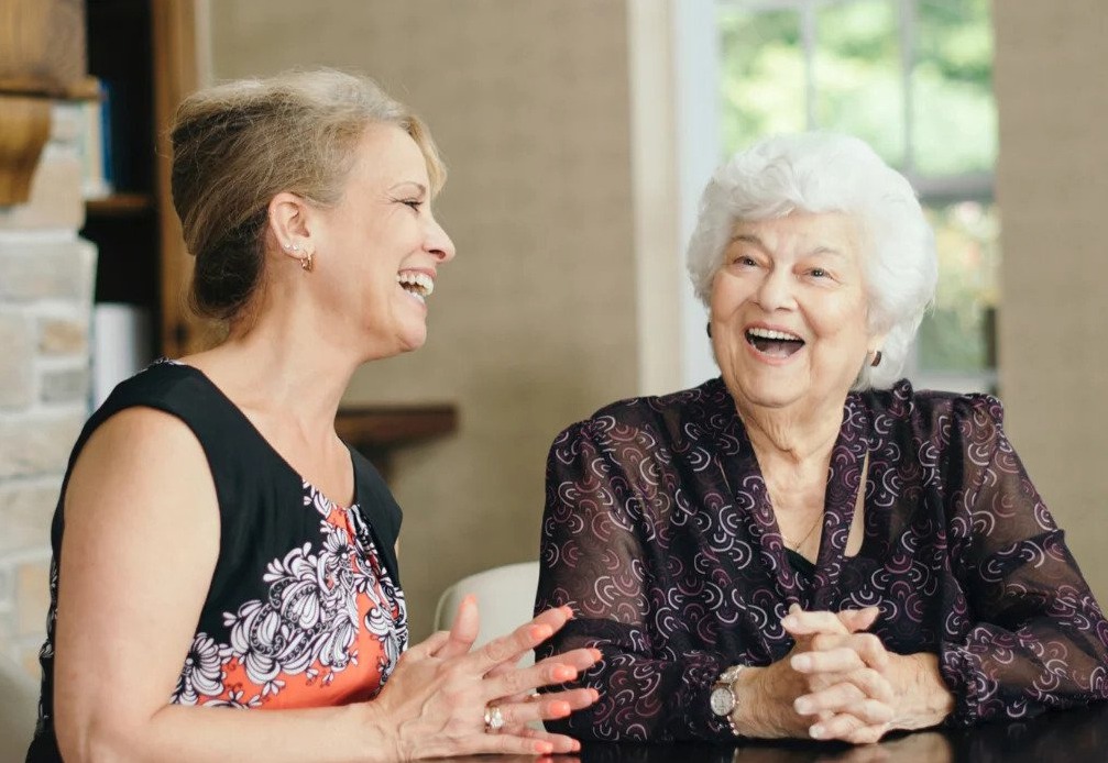 Senior woman laughing with staff member