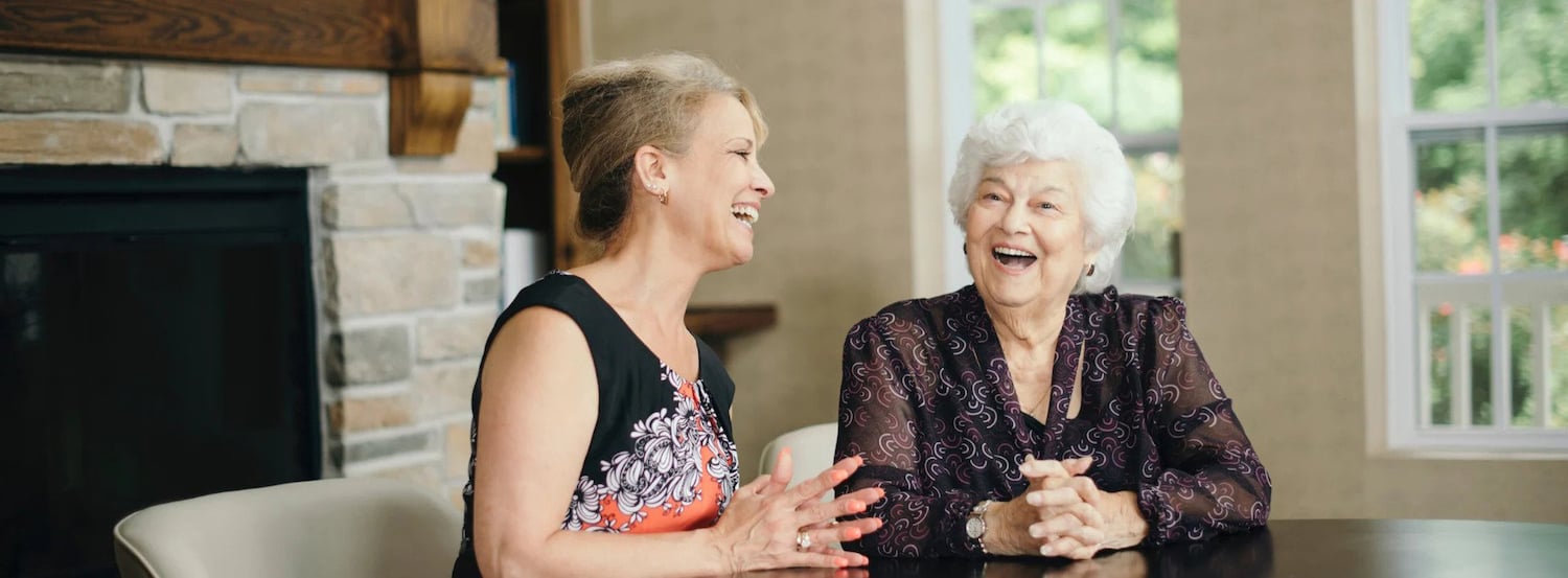 Senior living resident having conversation with woman at a table