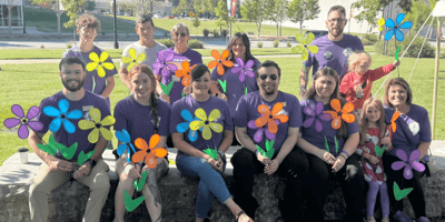 A Cedarhurst fundraising team posing and holding colorful paper flowers at an Alzheimer's Association event.