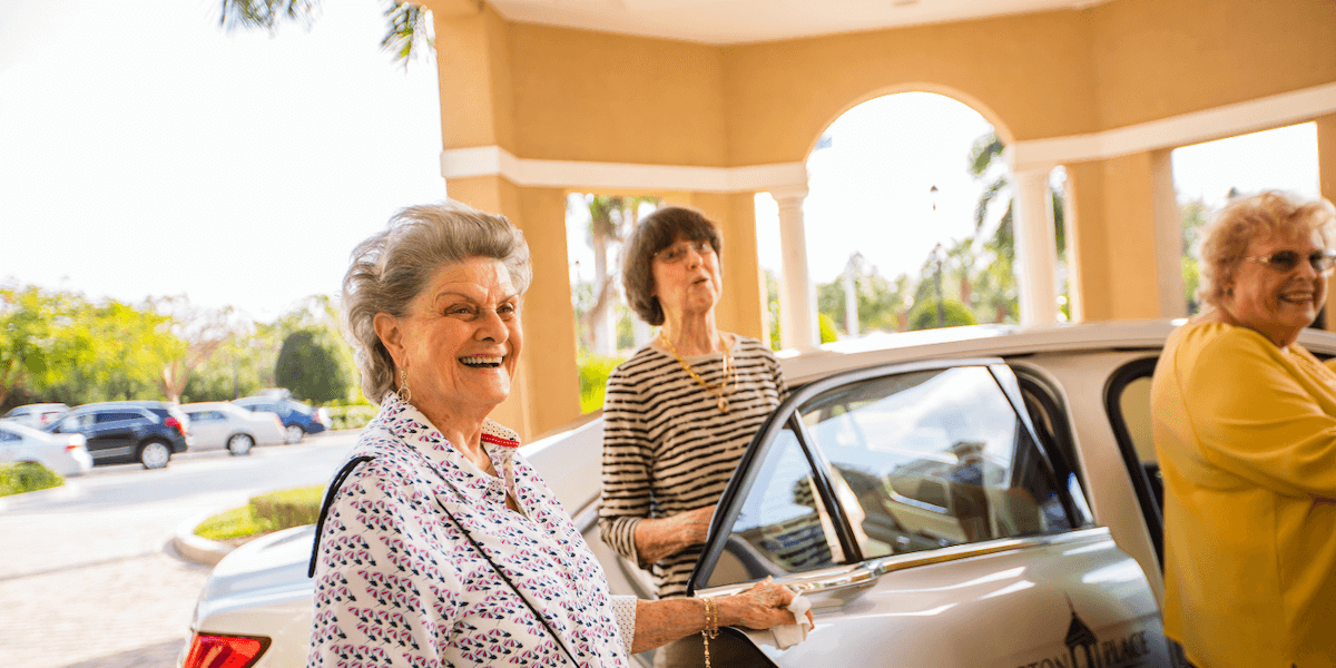 Three women smiling outside of a car