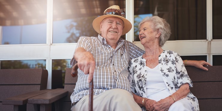 A couple in a senior living community sitting outdoors.