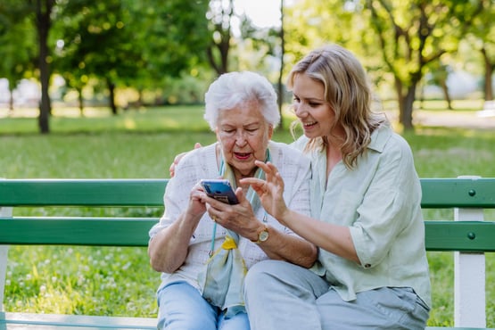 Senior woman looking at communication apps for senior living with her adult daughter.