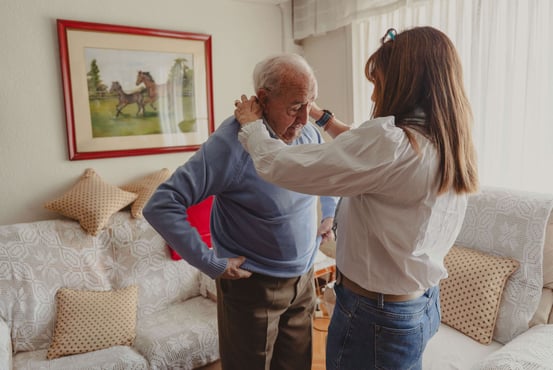 Daughter helping her senior father get dressed.
