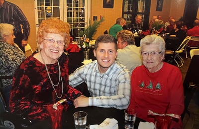 A young Almir Sajtovic poses with two senior living residents at a holiday party.