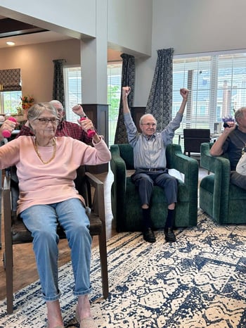 A group of seniors seated and participating in chair exercises.