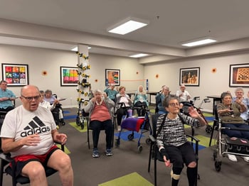 A group of senior living residents participating in a Chair One Fitness class at their community.