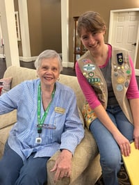 A girl scout and a senior living resident ambassador smile for a photo.