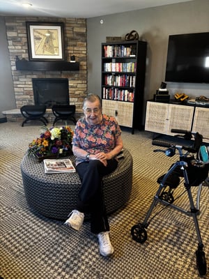 A senior woman sits in her senior living community's library.