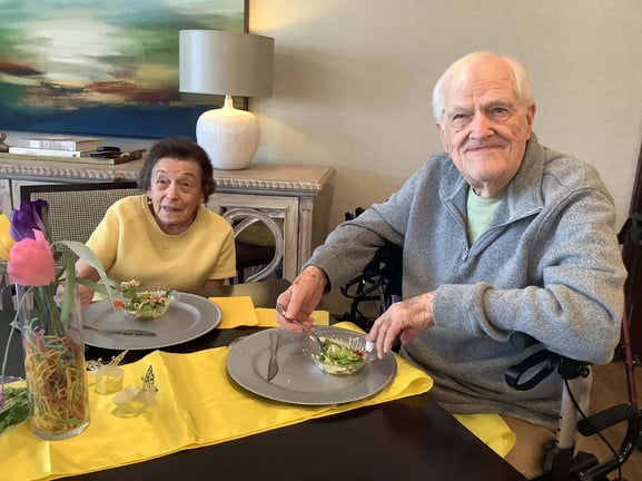 A senior couple smiling and enjoying dinner together.
