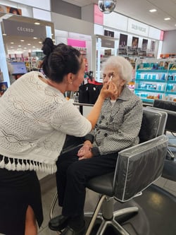 A senior woman receives a makeover at the beauty counter of a department store.