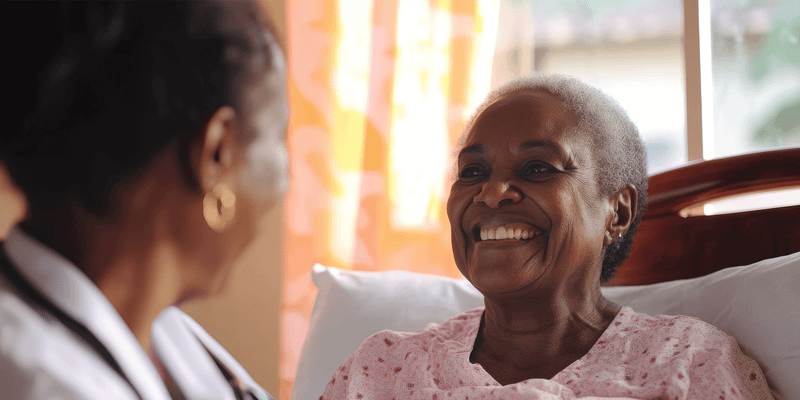  Happy senior woman in respite care smiles while being cared for by a senior living staff member