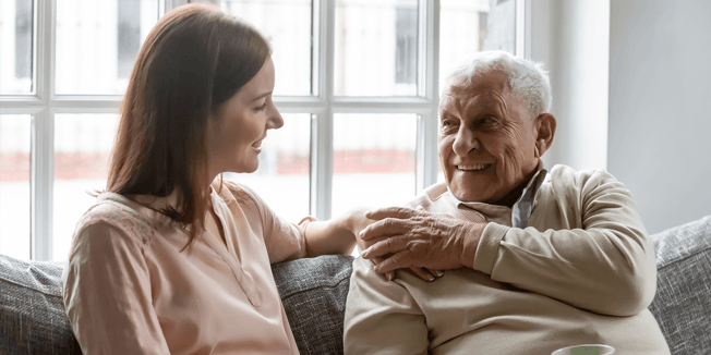 Smiling young woman sitting on sofa with senior father enjoying pleasant conversation