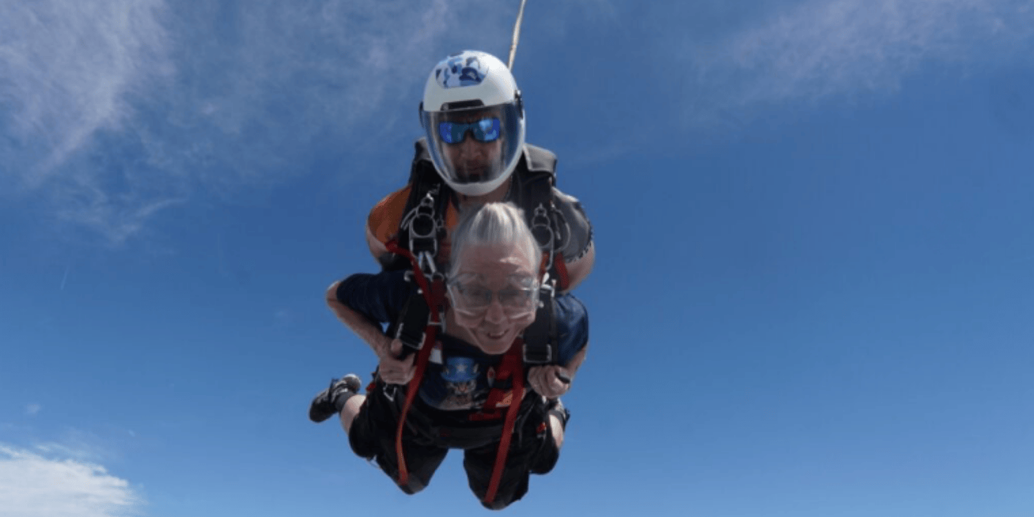 A senior woman skydives with an instructor.