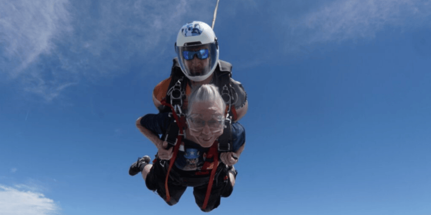 A senior woman skydives with an instructor.