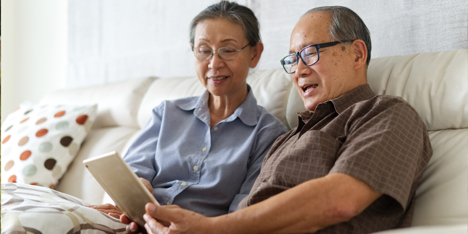 Senior couple looking at tablet on couch