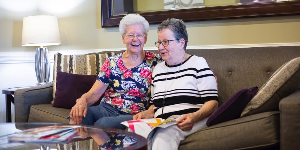 Two memory care residents socializing over a magazine