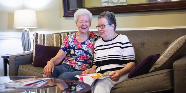 Two memory care residents socializing over a magazine