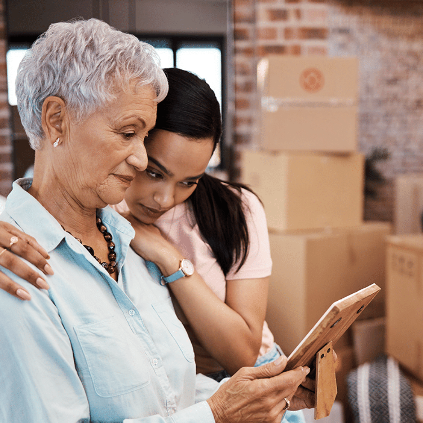Mother and daughter pack moving boxes while looking at photo