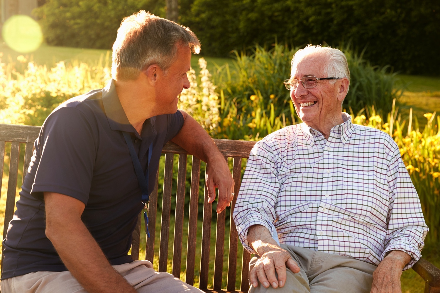 Caregiver talking with senior on a bench in the garden Caregiver talking with senior on a bench in the garden
