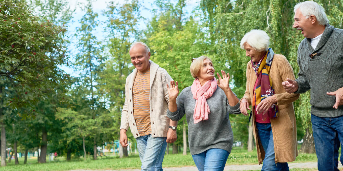 Four senior friends walking and talking in the garden