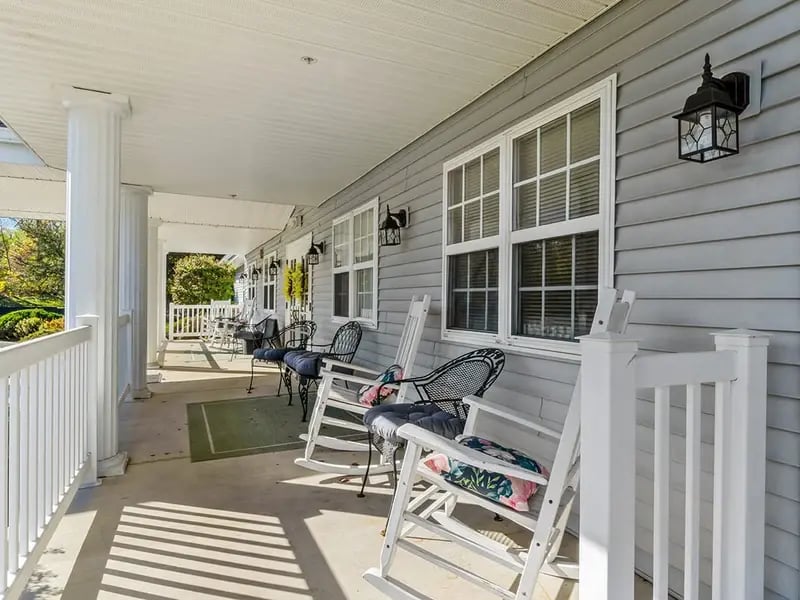 An accessible covered porch at Cedar Creek of Fort Wayne equipped with rocking chairs and fans