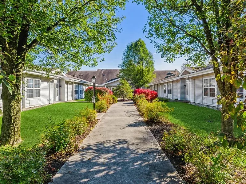 An inviting outdoor area at Cedar Creek of Fort Wayne, showing lush green spaces and paved paths,
