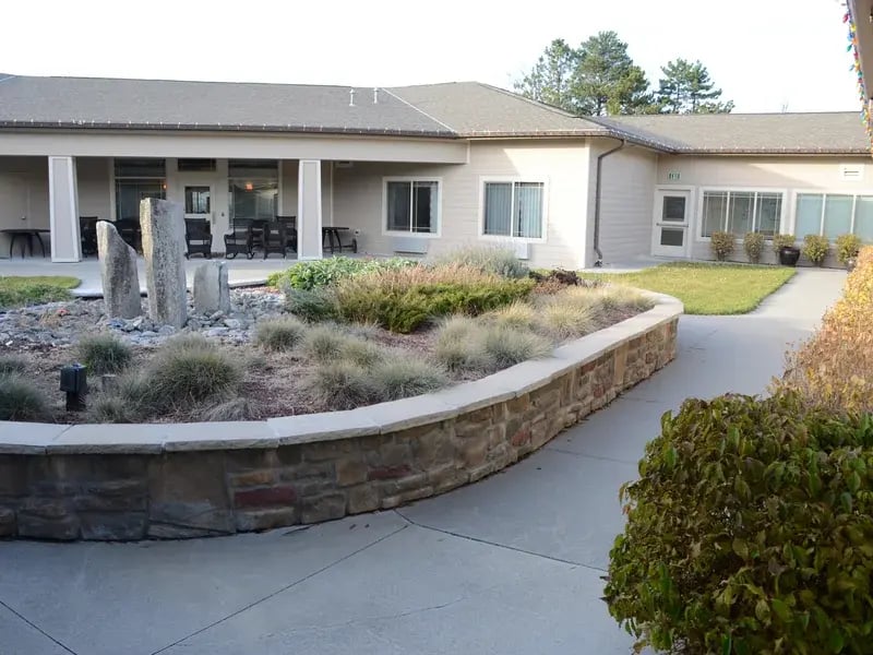 An inviting outdoor area at Cedar Creek of High Plains, showing lush green spaces and paved paths.