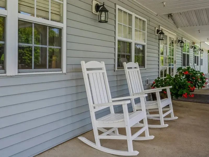 An accessible covered porch at Cedar Creek of Logansport equipped with rocking chairs and fans