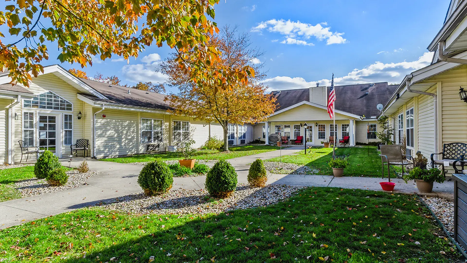 An inviting outdoor area at Cedar Creek of Muncie, showing lush green spaces and paved paths,