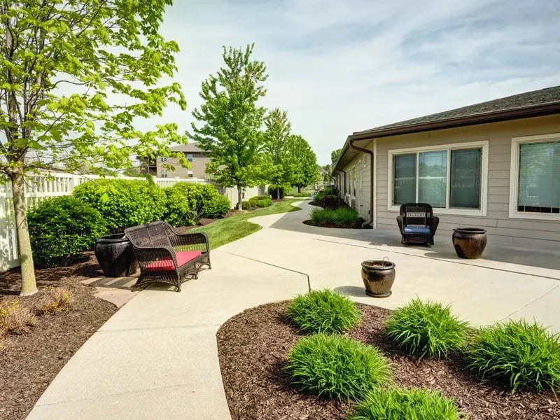 An inviting outdoor area at Cedar Creek of Prairie Meadows, showing lush green spaces and paved paths.