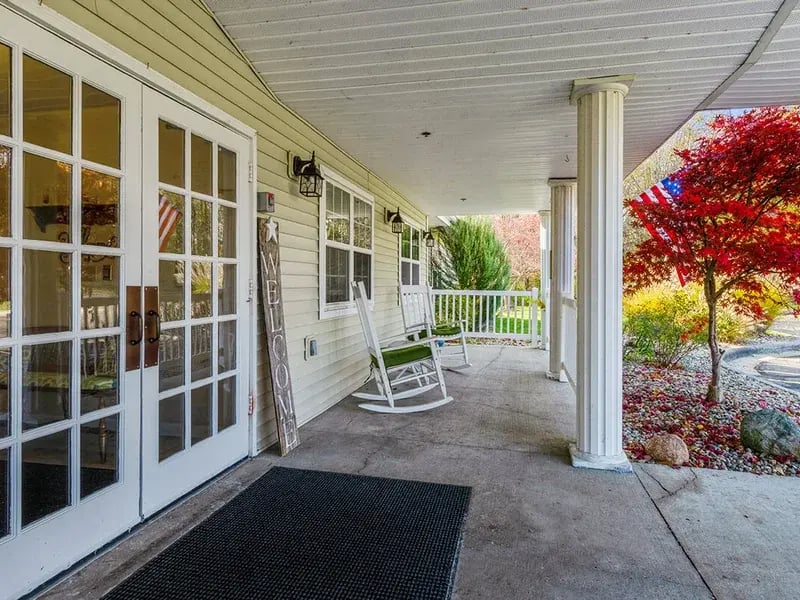 An accessible covered porch at Cedar Creek of Warsaw equipped with rocking chairs and fans